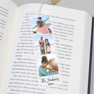 May include: A personalized bookmark featuring three family photos. The bookmark includes the text "The Jacksons" and the year "2025". It is hanging from a book.