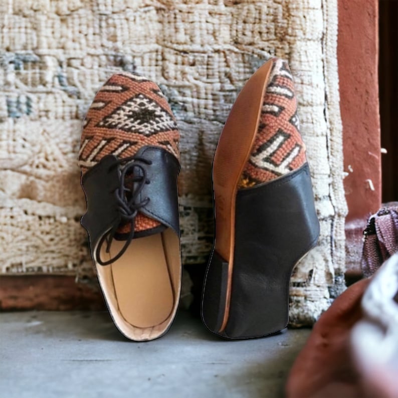May include: Pair of handmade leather shoes with a woven textile upper in shades of brown, tan, and black. The shoes have a black leather toe cap and laces. The soles are a light brown color.