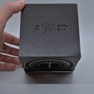May include: A black cube with a speaker on the bottom. The cube has the text "A 3D" embossed on the top.