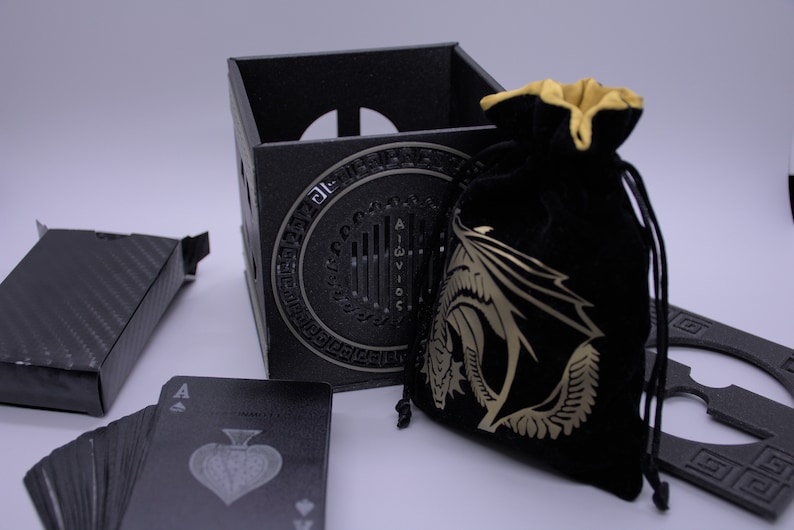 May include: A black playing card deck, a black box with a dragon design, a black velvet bag with a gold dragon design, and a black card holder with a dragon design.