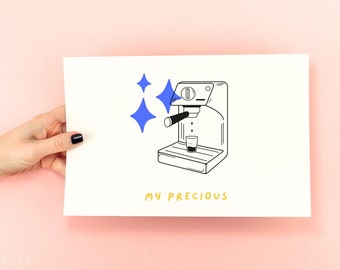 May include: A black and white illustration of an espresso machine with blue starbursts and the words "MY PRECIOUS" in yellow. The image is on a white background and held by a hand with black nail polish.