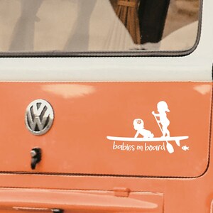 May include: White vinyl sticker with a silhouette of two children on a paddleboard. The text "babies on board" is below the image.