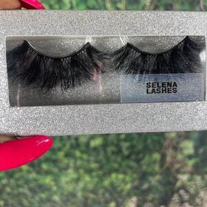 May include: A pair of black false eyelashes in a silver glitter box with the text "SELENA LASHES" on the front.
