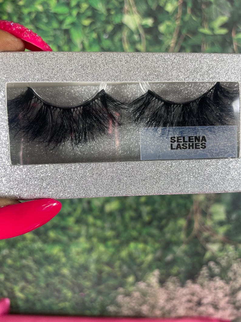 May include: A pair of black false eyelashes in a silver glitter box with the text "SELENA LASHES" on the front.