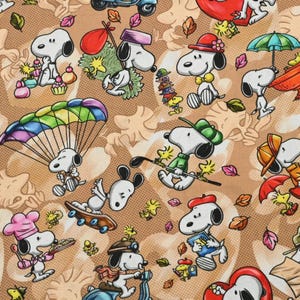 Peut inclure: Un tissu beige avec un motif répétitif de Snoopy et Woodstock dans diverses activités, incluant le parachutisme, le skateboard, la cuisine et la trottinette, parsemé de feuilles d'automne colorées sur un fond à texture pointillée.