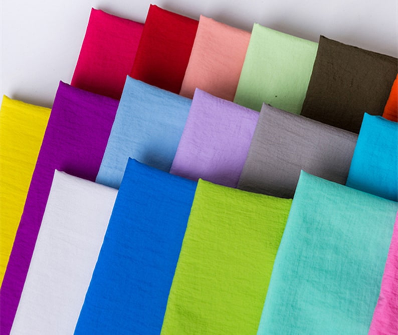 K&ouml;nnte beinhalten: Eine Sammlung von Stoffproben in verschiedenen Farben, darunter Gelb, Lila, Blau, Wei&szlig;, Gr&uuml;n und Rosa. Der Stoff hat eine weiche, strukturierte Oberfl&auml;che.