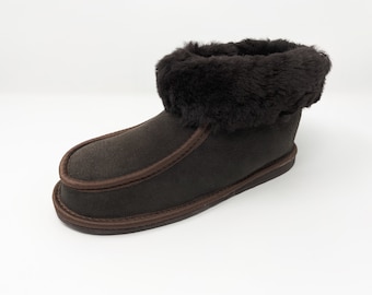 Op de afbeelding: Bruine suède pantoffel met een bruine imitatiebont manchet. De pantoffel heeft een bruin stiksel detail rond de rand.