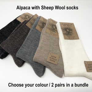 May include: Five pairs of alpaca and sheep wool socks in different colours: dark grey, brown, grey, beige, and white. Each pair has a brown tag with the text "Sheepwool with 40% Alpaca" and "With Alpaca Wool".