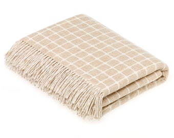 May include: A beige throw blanket with a white geometric pattern and fringe trim.