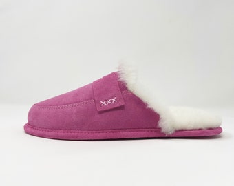 May include: Pink suede slipper with a white faux fur lining and a strap across the top with the word "XXX" stitched on it.