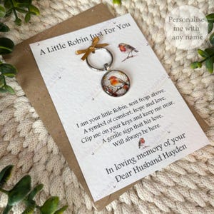 A keyring with a round pendant showing a watercolour robin on a branch. The keyring is attached to a card with the text "A Little Robin Just For You" and a poem about comfort and love.