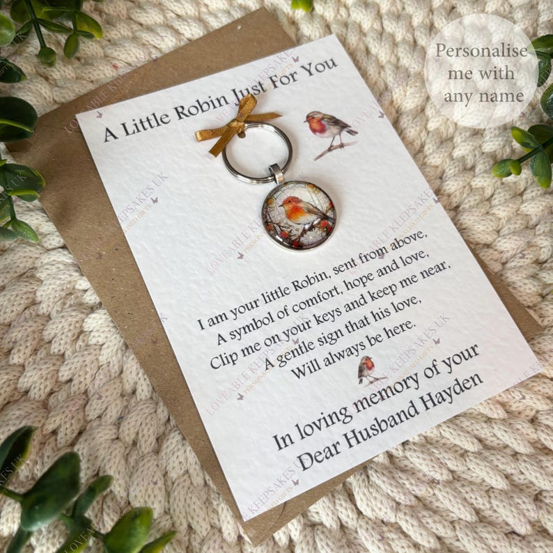 A keyring with a round pendant showing a watercolour robin on a branch. The keyring is attached to a card with the text "A Little Robin Just For You" and a poem about comfort and love.