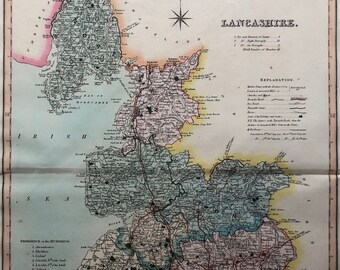 May include: A vintage map of Lancashire, England, with detailed borders of the different districts. The map is colored in shades of blue, green, pink, and yellow. The map includes a compass, a scale, and a key with explanations of the symbols used.