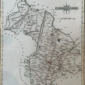 Op de afbeelding: Een vintage kaart van Cambridgeshire, Engeland, met gedetailleerde plaatsnamen en geografische kenmerken. De kaart heeft een decoratieve rand, een kompasroos en een schaal. De tekst "CAMBRIDGESHIRE" staat bovenaan.