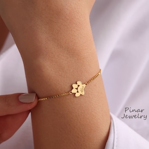 May include: Gold chain bracelet with a paw print charm engraved with the name "Alex".