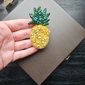 May include: A yellow and green beaded pineapple brooch. The pineapple is made of yellow beads and the leaves are made of green beads.