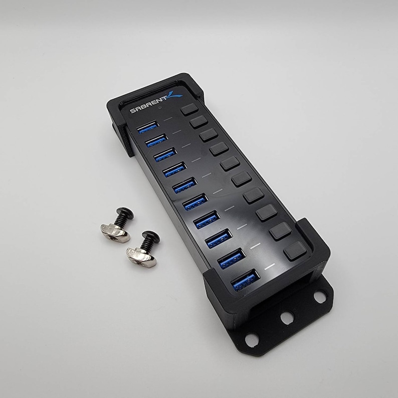 May include: Black USB hub with 10 ports and the text "SABRENT" on the side. The hub is mounted on a black bracket with four screw holes. Two silver screws are included.
