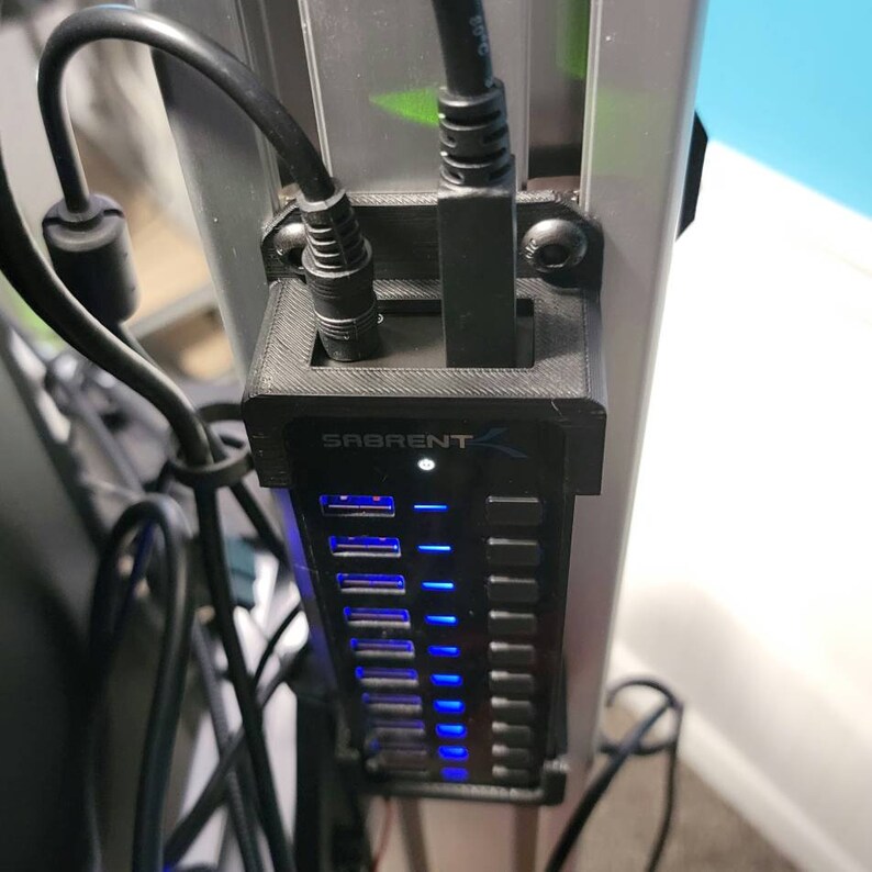 May include: A black USB hub with a blue LED light, mounted to a silver pole. The hub has the text "SABRENT" printed on it.