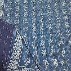 May include: A blue and white patterned quilt with a geometric design. The quilt features a repeating pattern of circles and dots, with a decorative border. The fabric appears to be cotton or a similar material.