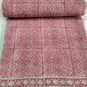 Puede incluir: Colcha kantha rosa y blanca con un patrón geométrico. La colcha tiene un borde con un diseño repetitivo.