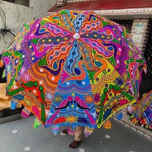 Puede incluir: Un paraguas grande y colorido con un dise&ntilde;o intrincado. El paraguas presenta un caleidoscopio de colores que incluyen naranja, rosa, azul y verde, con un patr&oacute;n repetido de p&aacute;jaros y motivos florales. El paraguas est&aacute; abierto, mostrando su forma decorativa completa.
