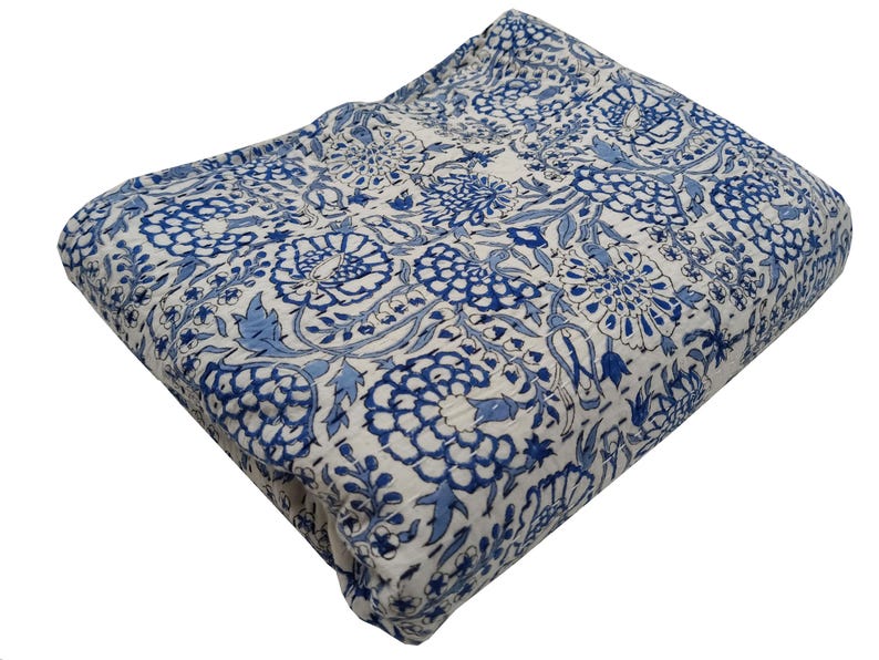 May include: A folded, quilted blanket with a white background and a repeating pattern of blue floral designs. The blanket is made of a soft, likely cotton material, and is suitable for use as a bedspread or throw.