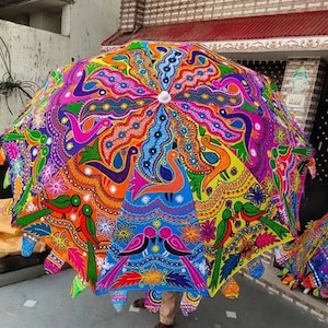 Puede incluir: Un paraguas grande y colorido con un dise&ntilde;o intrincado. El paraguas presenta un caleidoscopio de colores, incluyendo azul, naranja, rosa y verde, con un centro blanco. El dise&ntilde;o incluye motivos de pavo real y florales.