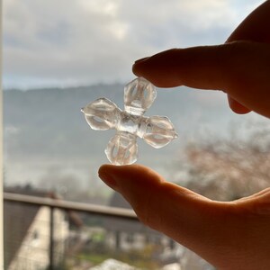 Peut inclure: Un objet transparent en forme de croix, doté de quatre branches symétriques évidées en forme de pétales partant d'un noyau central carré. L'article est composé d'un matériau translucide laissant passer la lumière à travers sa surface lisse.