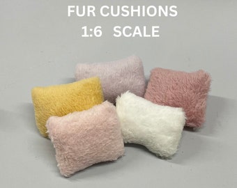 Könnte beinhalten: Fünf Miniatur-Fellkissen in verschiedenen Farben, darunter rosa, weiß, gelb und lavendel. Die Kissen sind auf einer hellgrauen Oberfläche angeordnet. Der Text "FUR CUSHIONS 1:6 SCALE" ist über den Kissen gedruckt.