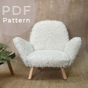 May include: A miniature white fuzzy armchair with wooden legs. The chair has a rounded back and armrests. The text "PDF Pattern" is in the upper left corner.