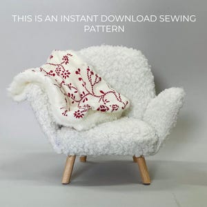 May include: A small, white, fluffy armchair with wooden legs holds a folded blanket. The blanket is white with a red floral pattern. Text at the top reads: "THIS IS AN INSTANT DOWNLOAD SEWING PATTERN."