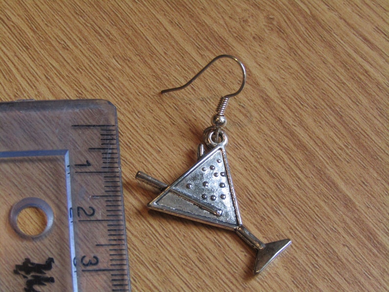 May include: Silver martini glass earring with a silver stir stick. The earring is about 1.5 inches long.