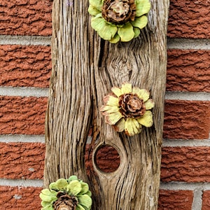 pine cone wall art, yellow flowers on rustic pine fence board