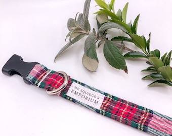 May include: Red, green, and white plaid dog collar with a black plastic buckle and a silver ring. The collar has a white label that says "Mr. Squidge's Emporium".