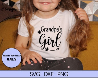 May include: A white t-shirt with the text "Grandpa's Girl" in black lettering with a heart and arrow design. A young girl is wearing the shirt and sitting on a yellow couch.