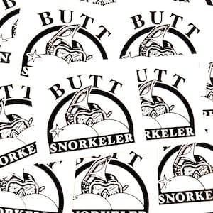 May include: White stickers with a black graphic of a snorkel mask and the word "BUTT" above it, and "SNORKELER" below. The design is enclosed in a black arch. A star is on the left side of the mask.