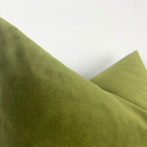 May include: A close-up of a green corduroy pillow with a subtle texture. The pillow is folded in half, showing the seam down the center.