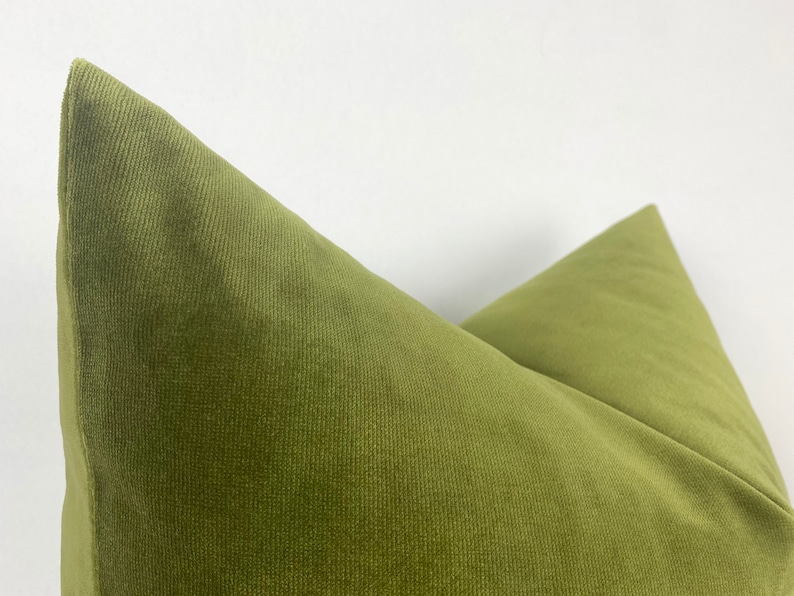 May include: A close-up of a green corduroy pillow with a subtle texture. The pillow is folded in half, showing the seam down the center.