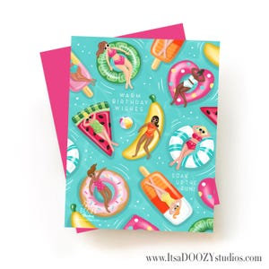May include: A greeting card with a turquoise background featuring illustrations of people floating on pool inflatables shaped like fruit, donuts, and popsicles. The text reads WARM BIRTHDAY WISHES and SOAK UP THE FUN. A bright pink envelope is visible behind the card.