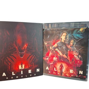 May include: A DVD case for the movie "Alien: Romulus" is open, revealing the disc and cover art. The cover art features a red and black image of an alien creature and the film's title. The disc case shows a group of people in a red and blue scene.