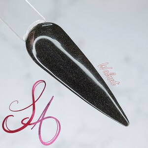 May include: A close-up of a dark gray nail polish with a subtle shimmer. The polish is called "Walnut".