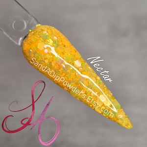 Puede incluir: Una muestra de uñas que muestra un polvo de inmersión con purpurina amarilla y verde vibrante llamado "Nectar". La muestra está en un palito transparente, mostrando el color y la textura. El texto "SandADipPowders.Etsy.com" y "Nectar" son visibles.