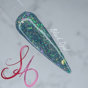 May include: A close-up of a light blue nail polish with iridescent glitter and gold flakes. The text "Black Opal" is written on the right side of the image.