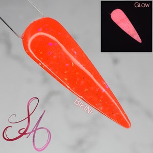 May include: Orange nail polish with iridescent glitter. The polish glows pink under a black light. The text "Bikini" is visible on the image.