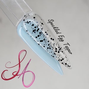 Könnte beinhalten: Nahaufnahme eines hellblauen Nagels mit schwarzen Punkten. Der Text "Speckled Egg Topper" ist in Schwarz auf weißem Hintergrund geschrieben.