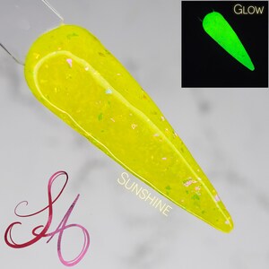 May include: A yellow nail polish with iridescent glitter. The polish glows in the dark, as shown in the inset image labeled "Glow". The text "SUNSHINE" is written on the image.