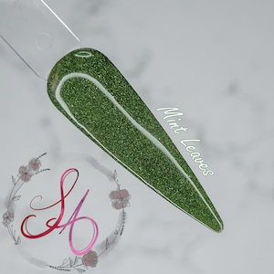 May include: A close-up of a green glitter nail polish with a clear base. The polish is called "Mint Leaves".