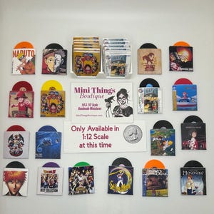 May include: A collection of miniature vinyl records with colorful sleeves featuring anime artwork, displayed with a white sign reading Mini Things Boutique 1:6 & 1:12 Scale Handmade Miniatures and Only Available in 1:12 Scale at this time.