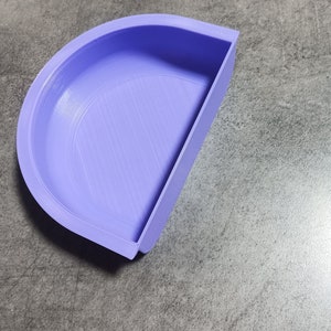 May include: A light purple plastic half-circle mold with a smooth, slightly textured surface. The mold is designed for crafting or creating projects.