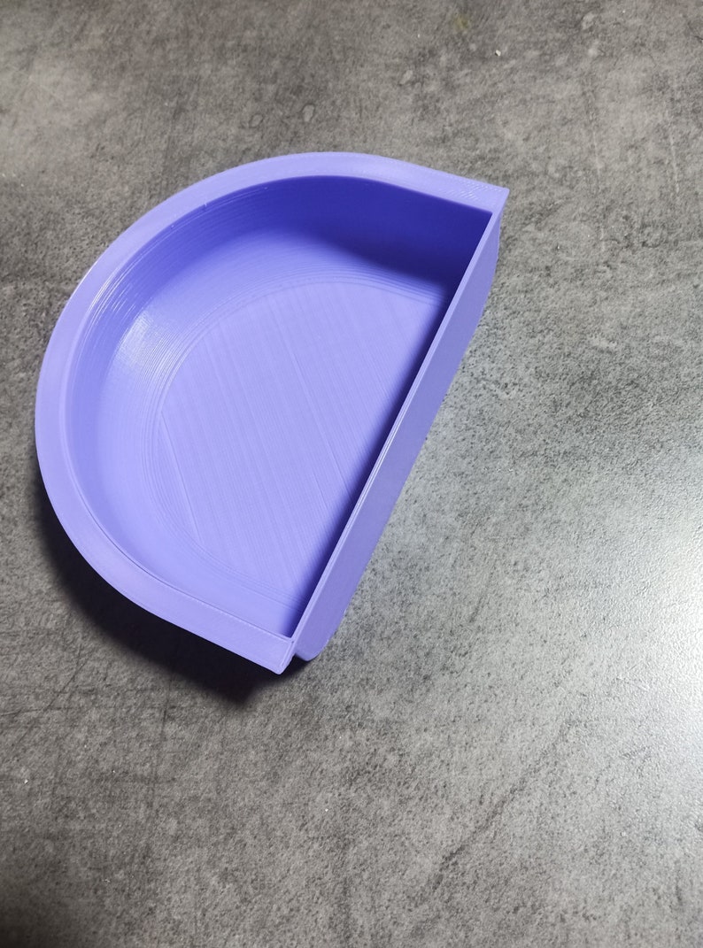 May include: A light purple plastic half-circle mold with a smooth, slightly textured surface. The mold is designed for crafting or creating projects.
